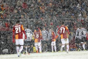 Players of Galatasaray and Juventus walk out of the pitch as their match is paused for 20 minutes due a heavy snowfall during their Champions League soccer match in Istanbul